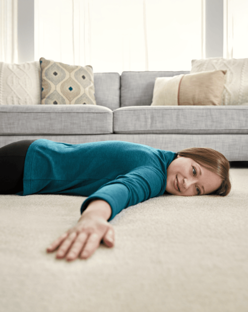 Woman enjoying soft carpet flooring in a cozy living room. Find premium carpet options at Carpet Master Carpet One, your local flooring expert.