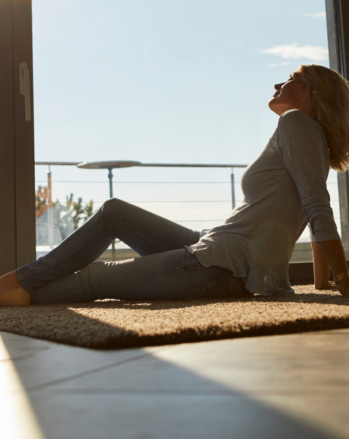 Woman relaxing on stylish luxury vinyl flooring. Explore durable and waterproof vinyl options at Carpet Master Carpet One, your local flooring store.