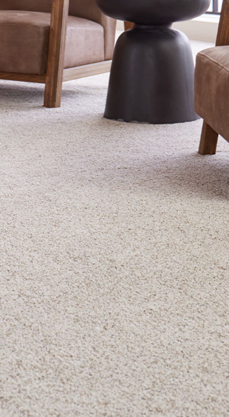Woman enjoying soft carpet flooring in a cozy living room. Find premium carpet options at Carpet Master Carpet One, your local flooring expert.
